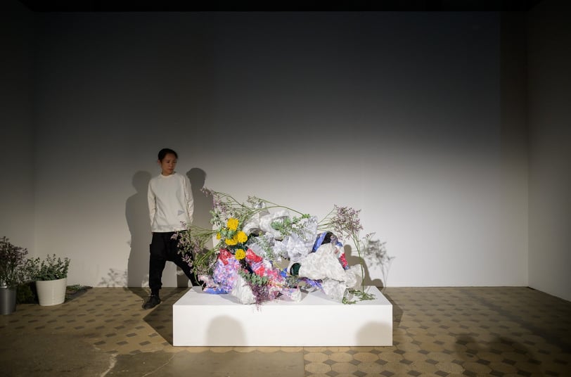 Hedy Leung interacting with the hand-built vessels and green materials during the performance