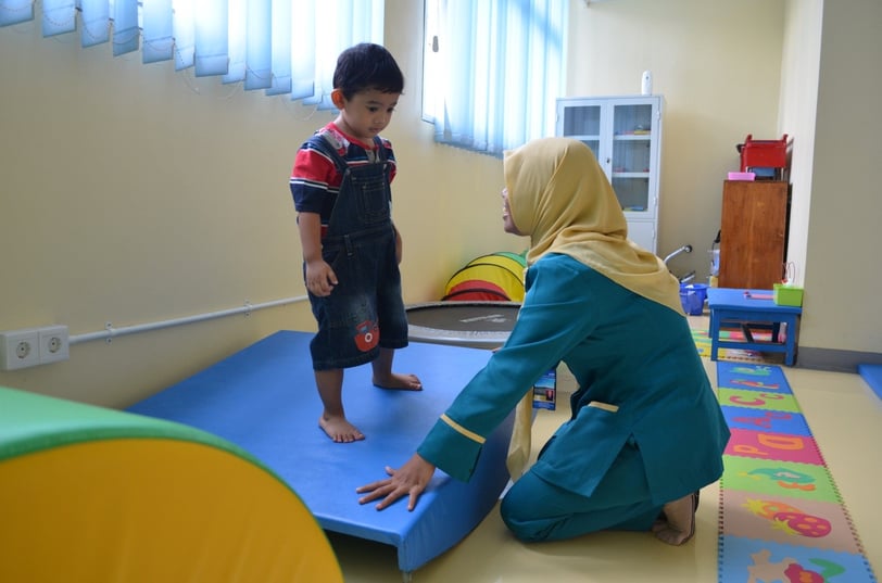 seorang anak yang sedang diterapi okupasi menggunakan alat terapi vestibular