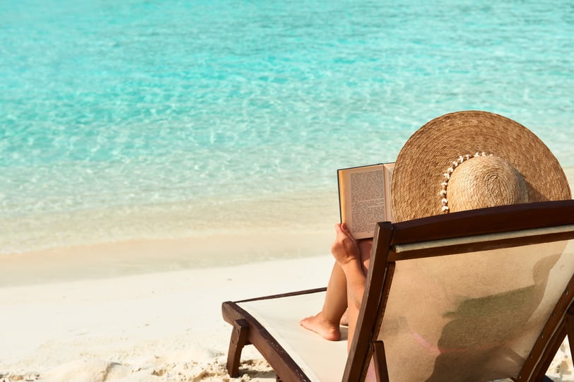 Woman reading on the beach in the Dominican Republic, best books to read on vacation