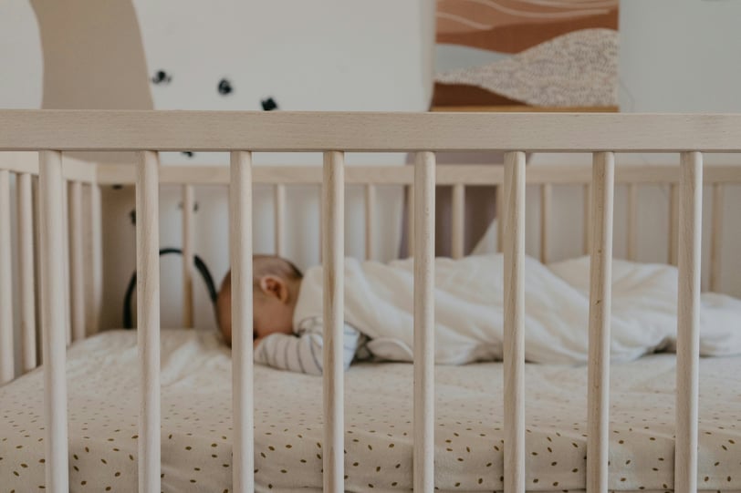 a baby in a crib with a white blanket