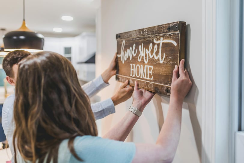 a couple of people hanging a wooden sign
