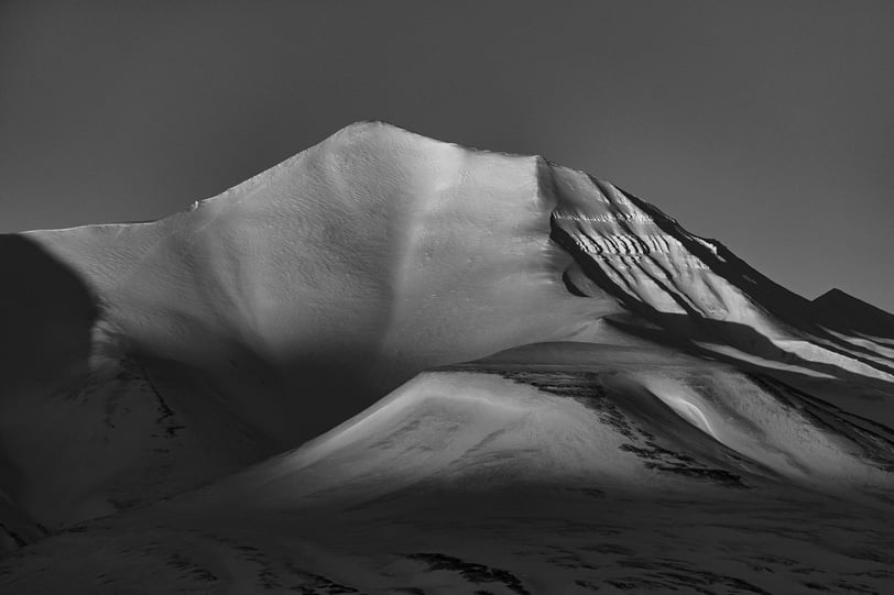 a snow covered mountain in black and white
