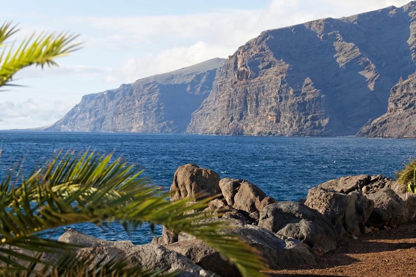 Vista de la costa rocosa de Tenerife con montañas y mar, un entorno natural ideal para terapias de bienestar y relajación emo