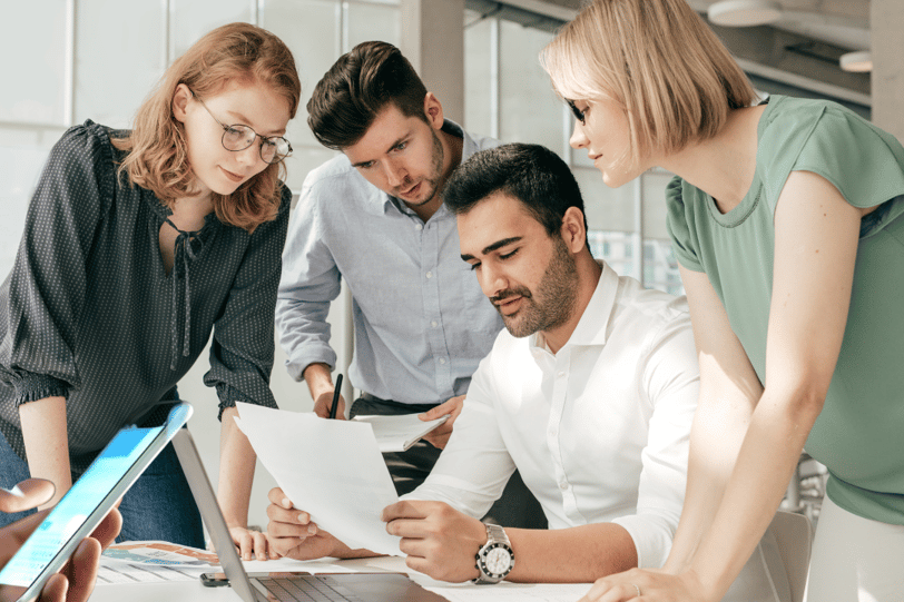 a group of people standing around a laptop computer