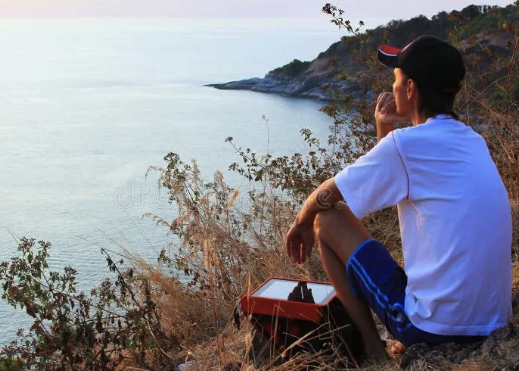a man sitting on a hill with a tablet computer