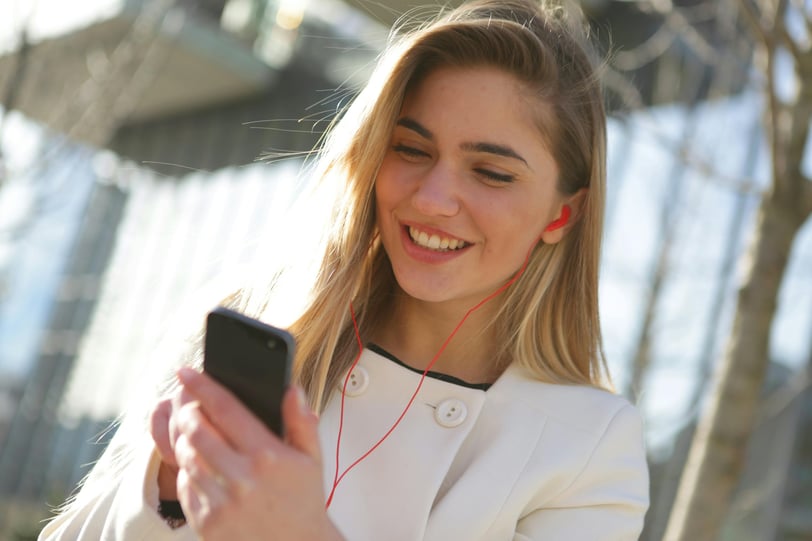 a woman in a white jacket and earphones is smiling