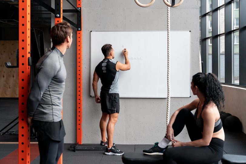 personal trainer writing workout plan on board