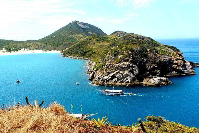 acantilado con una playa debajo y un barco navegando