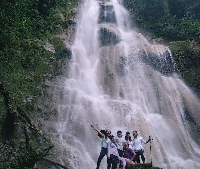 a group of people standing around a waterfall