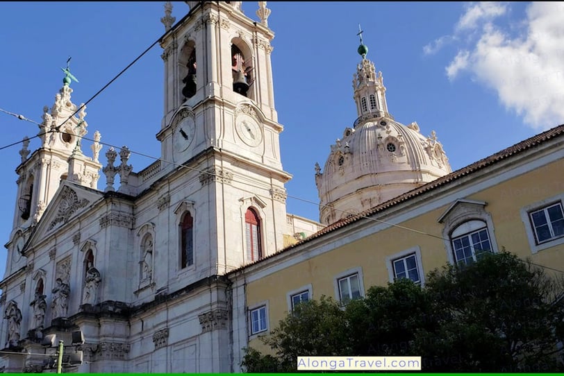 white building with a dome and twin bell towers are seen from tram 28 wagon in Lisbon