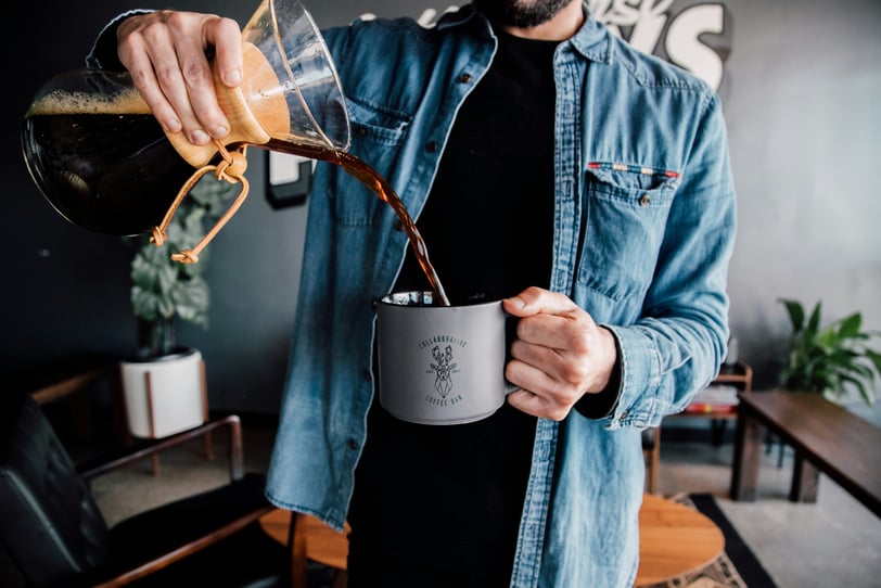 a guy pouring coffee from a chemex into a mug