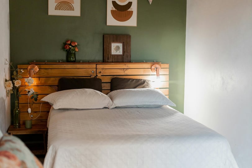 a bedroom with two beds and a wooden headboard green accent wall