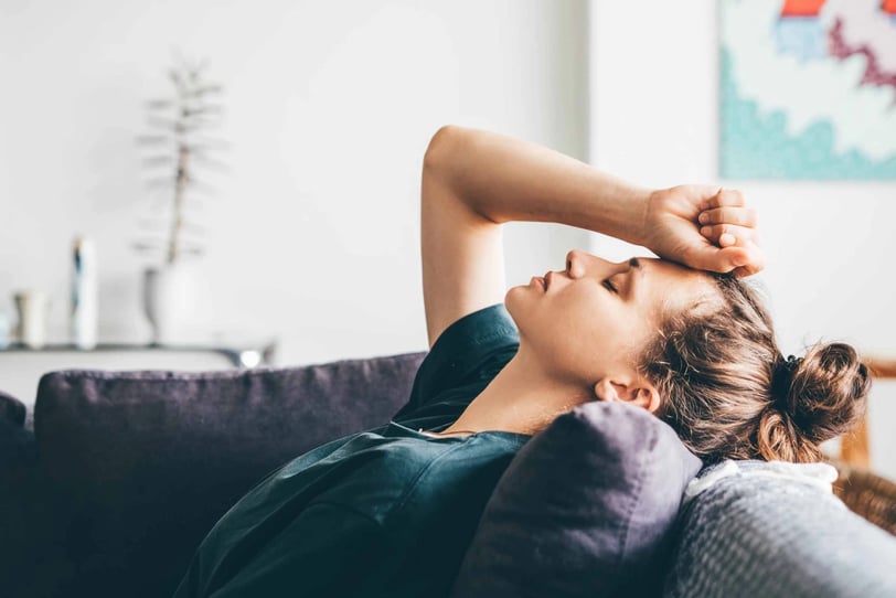 a woman is laying on a couch suffering with pain