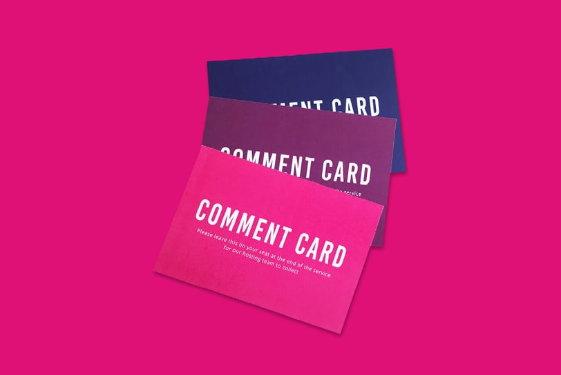 A stack of three event comment cards in pink, maroon, and navy blue.