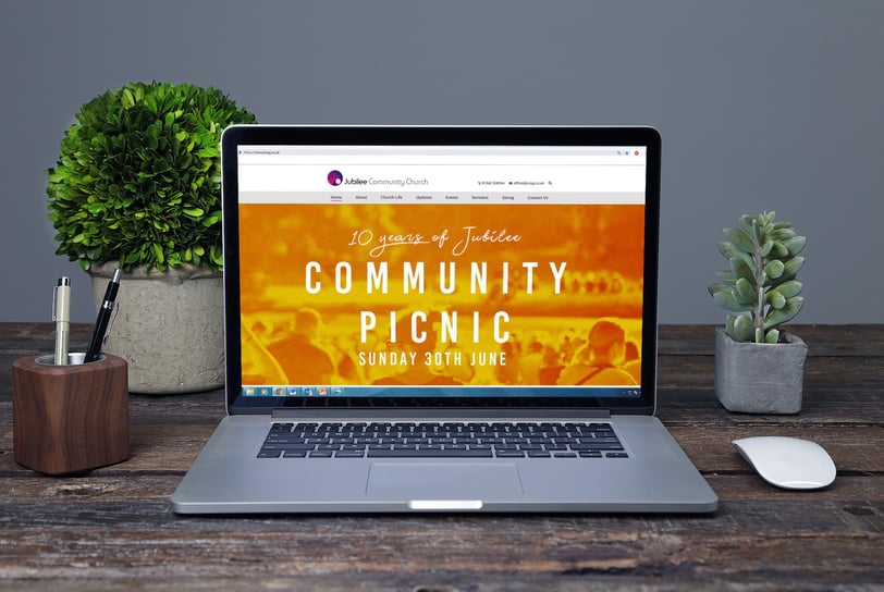 Laptop screen displaying Jubilee Community Church’s website with a Community Picnic event banner.