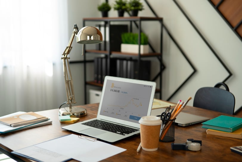 a laptop computer sitting on a desk with a lamp, pencil cup, paperwok, and a cup of coffee