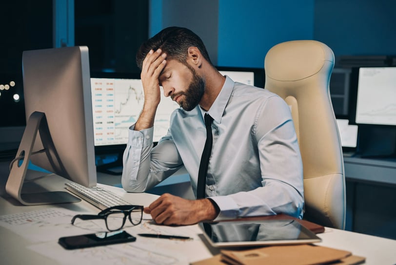 Stressed businessman sitting at his desk with his head in his hand