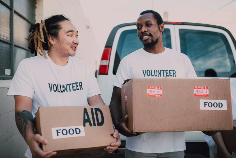two men in white shirts are holding boxes with boxes