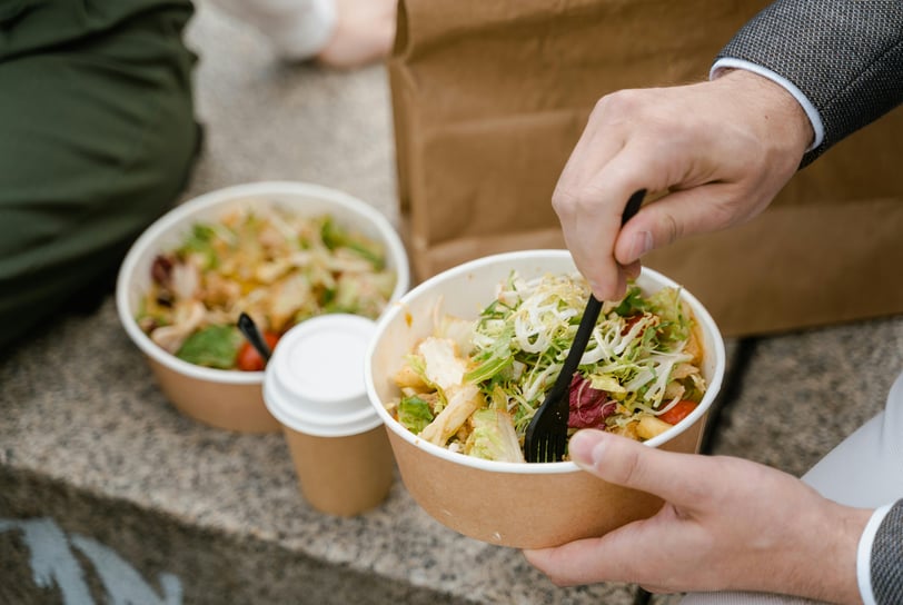 a person is eating a salad in a paper bag