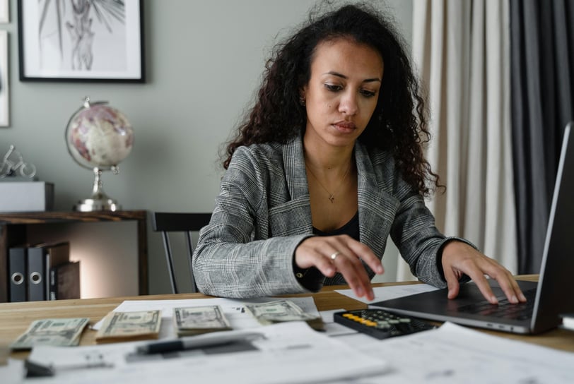 a woman sitting at a desk with a laptop and a calculator