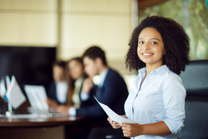 a woman in a business suit is smiling and holding a piece of paper