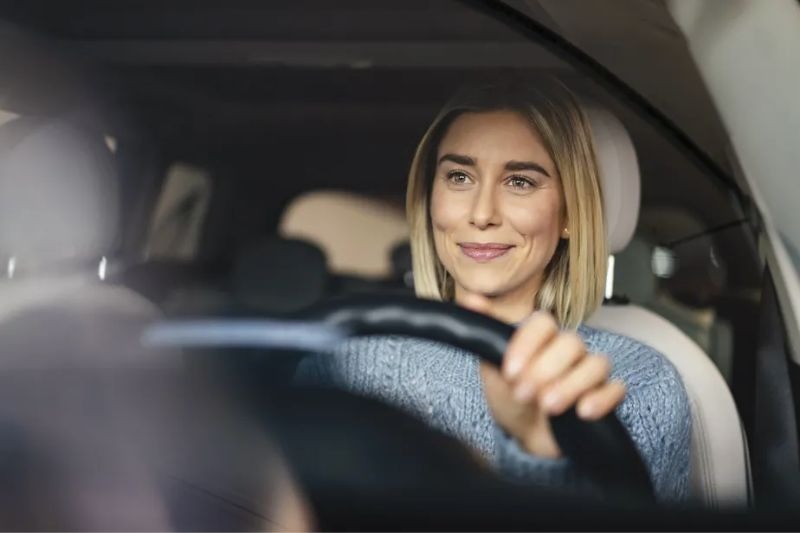 a woman driving a car with a steering wheel