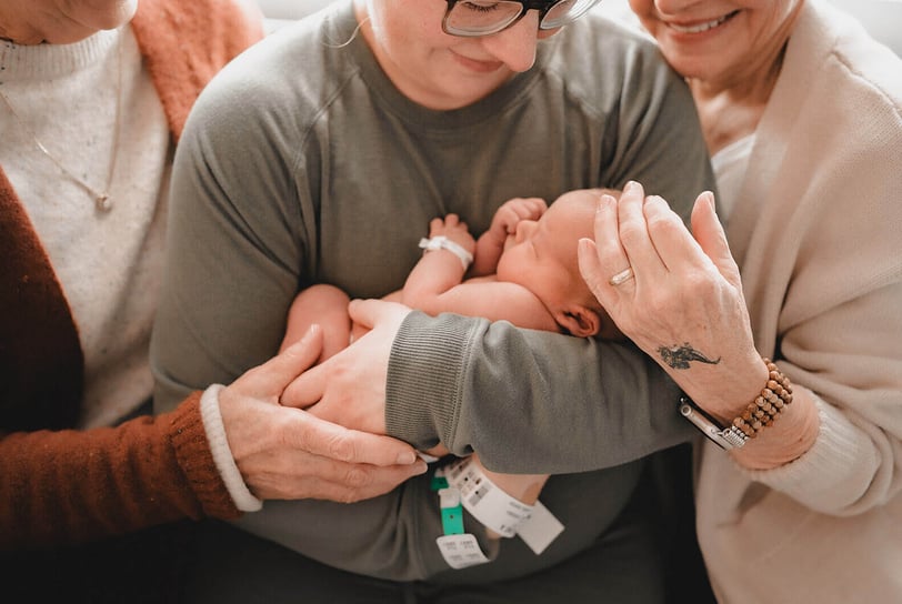 Both grandmas on either side of new mama in hospital bracelets