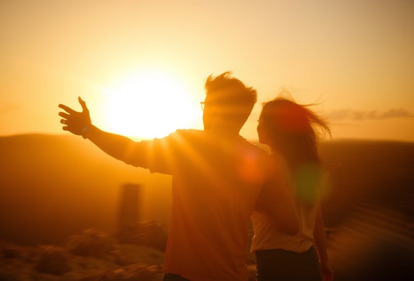 a couple standing in front of a sunset