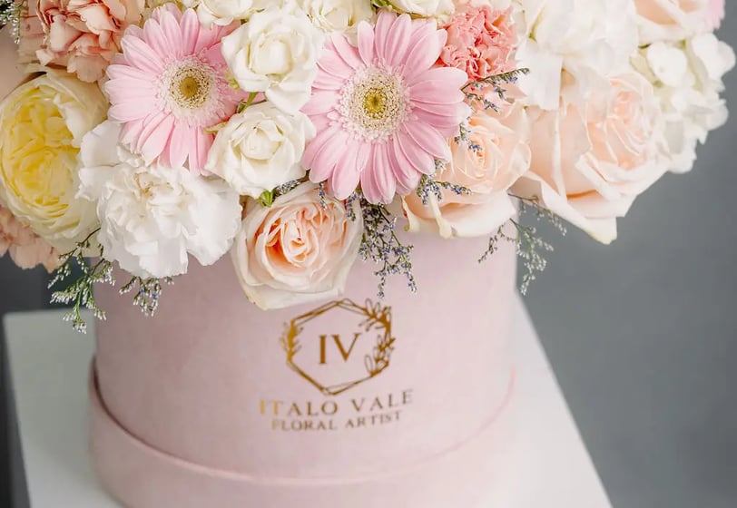 Elegant pink and white floral arrangement in branded pastel pink box