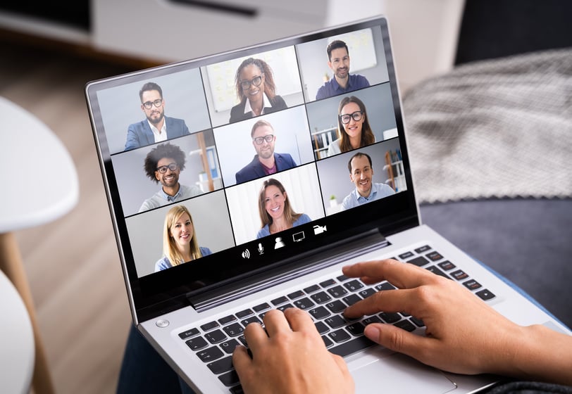 A person with a laptop participating in a virtual team meeting