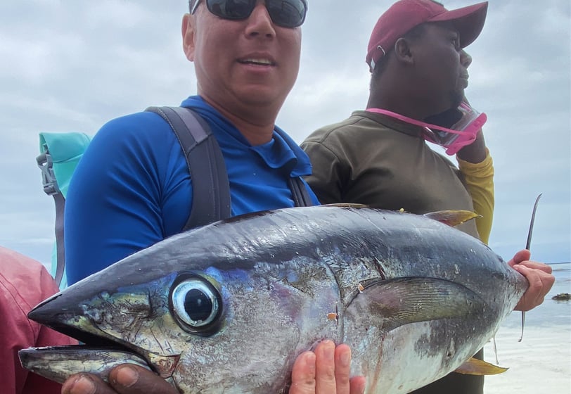 A beginner angler proudly holding a fish caught during a Zanzibar Angler's Paradise fishing trip, wi