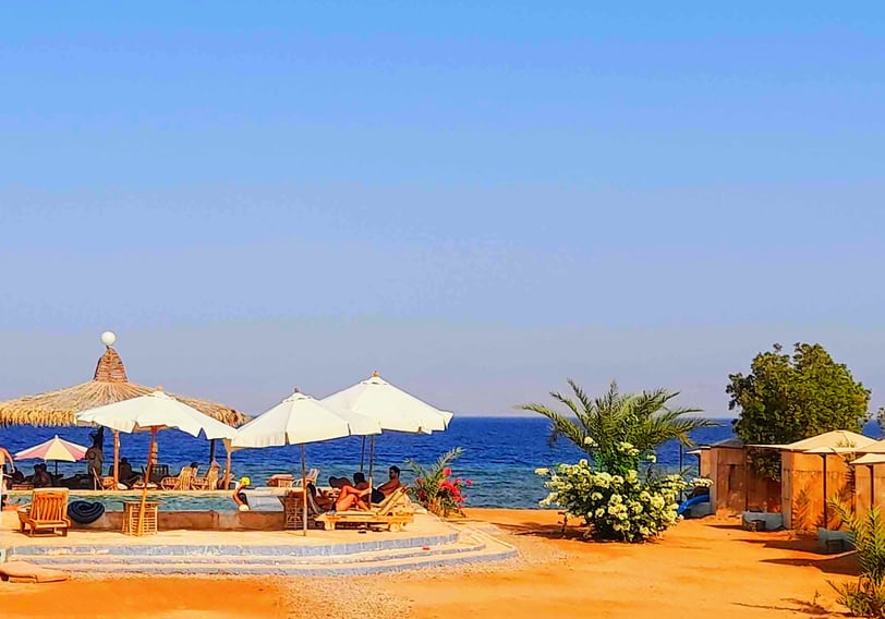 una spiaggia con ombrelloni e una piscina con gente sulla sabbia