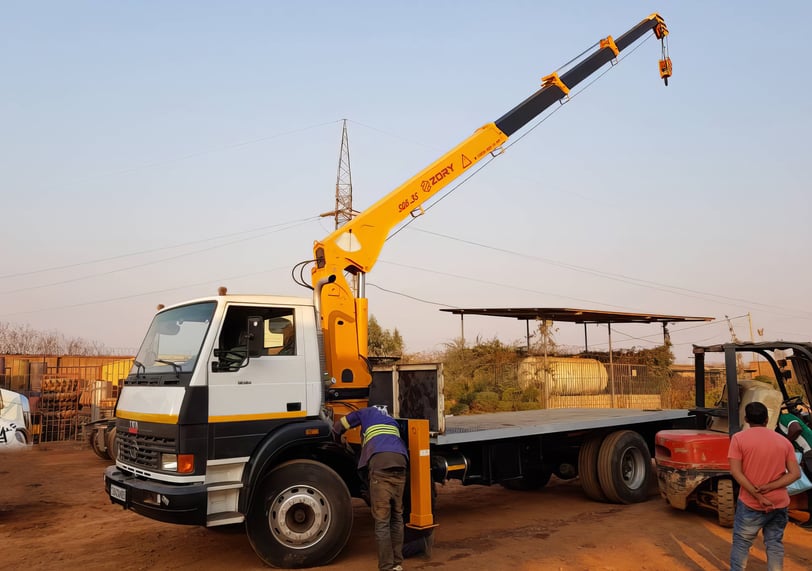 A telescopic boom truck mounted crane lifting a truck.