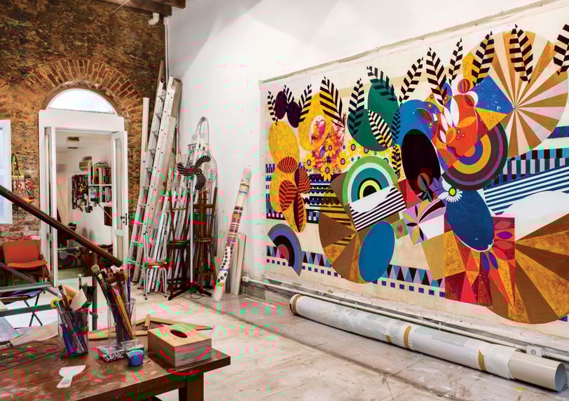 Ateliê de Beatriz Milhazes, colorido e cheio de obras e materiais de arte.
