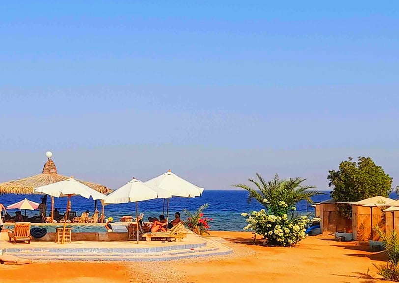 plaża z parasolami i basen z ludźmi na piasku