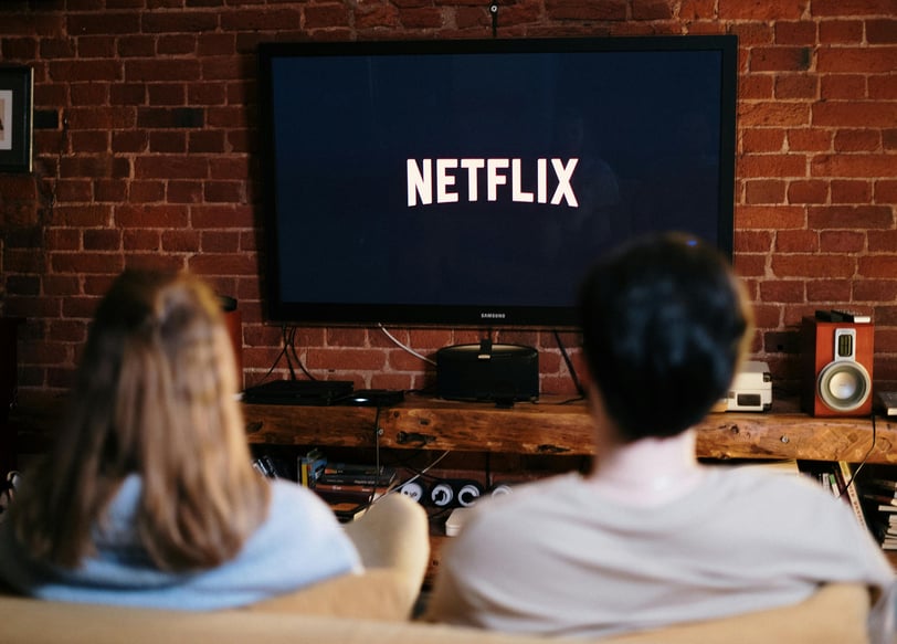 a man and woman sitting on a couch watching a tv