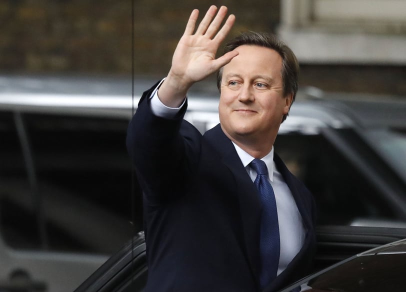 David Cameron in a suit and tie is waving his hand