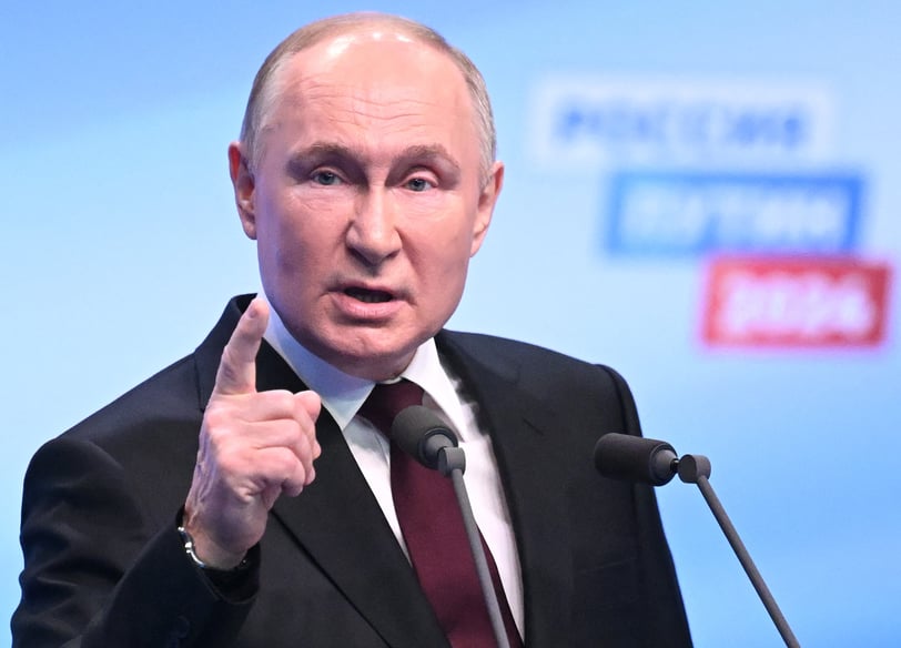 Vladimir Putin in a suit and tie is giving a speech