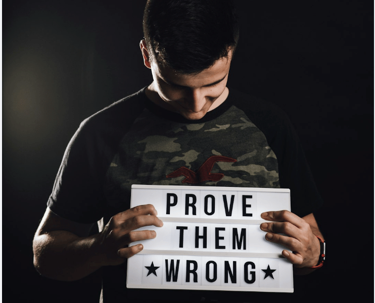 a man holding a sign that says prove them wrong