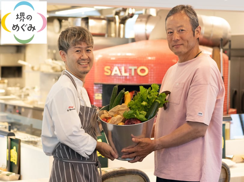 堺産農作物「堺のめぐみ」のロゴと共に、SALTOシェフ吉本さんと「じいじのバケツ」中井さんが新鮮な堺産野菜を手に店内で並ぶFARM TO TABLEの連携イメージ写真。