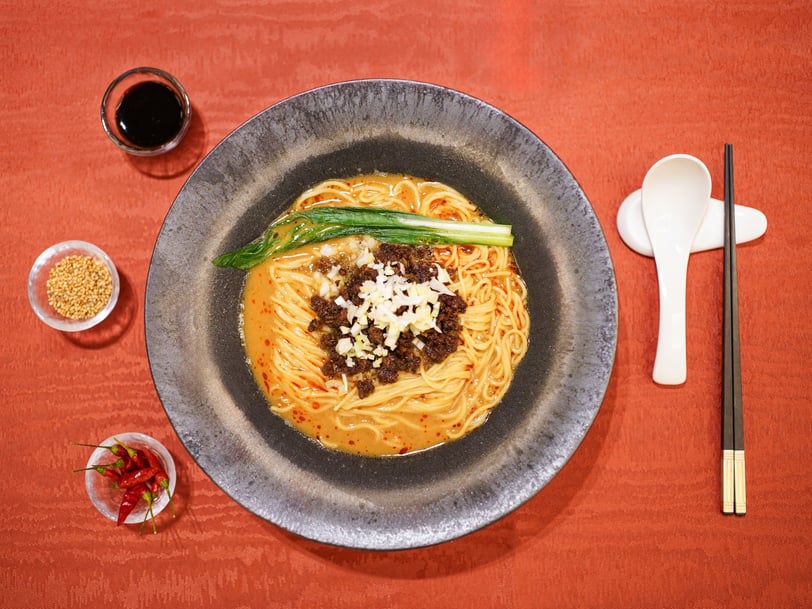 ホテル アゴーラ リージェンシー 大阪堺「龍鳳」の堺の味わい担々麺。金胡麻や鷹の爪を使い、具材やスープ、器、箸が並ぶ料理写真。
