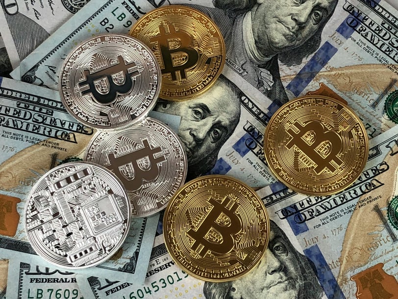 a bunch of bitcoin coins sitting on top of a pile of money