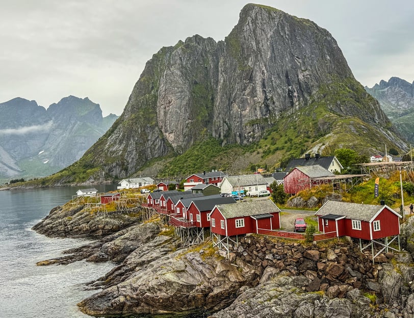 Ikoniske røde rorbuer ved sjøen i Hamnøy, Lofoten, omgitt av majestetiske fjell og arktisk kystlands
