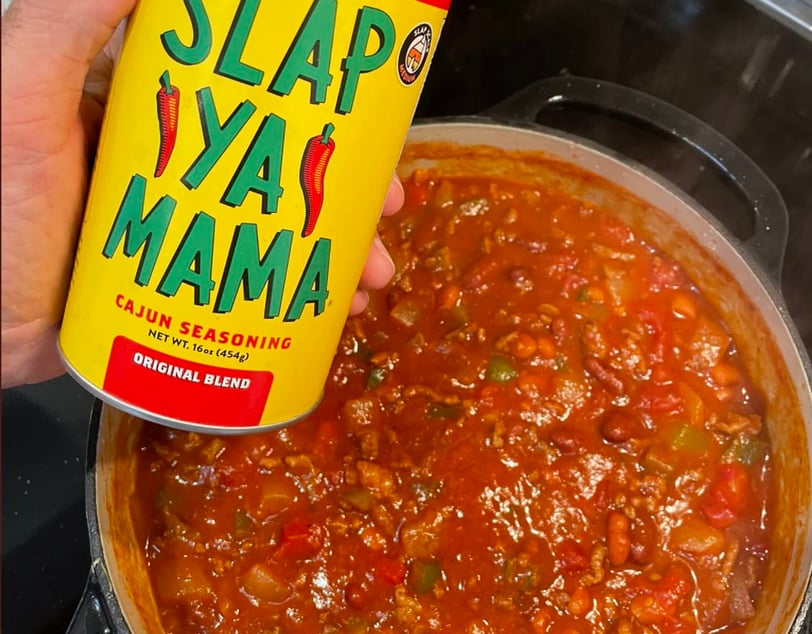 a person holding a can of slap ya ya mama chili sauce