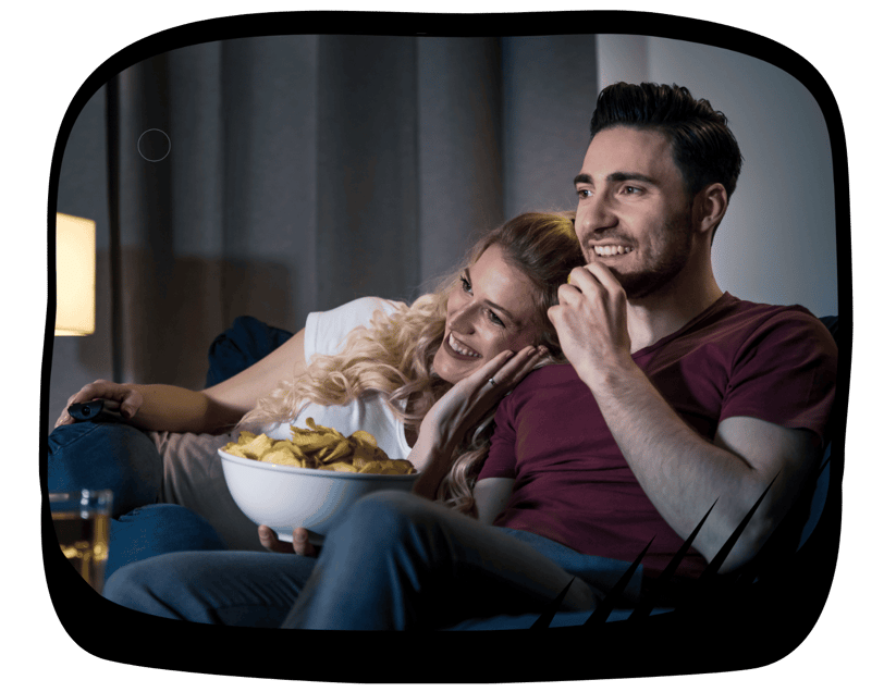 a man and woman sitting on a couch watching tv