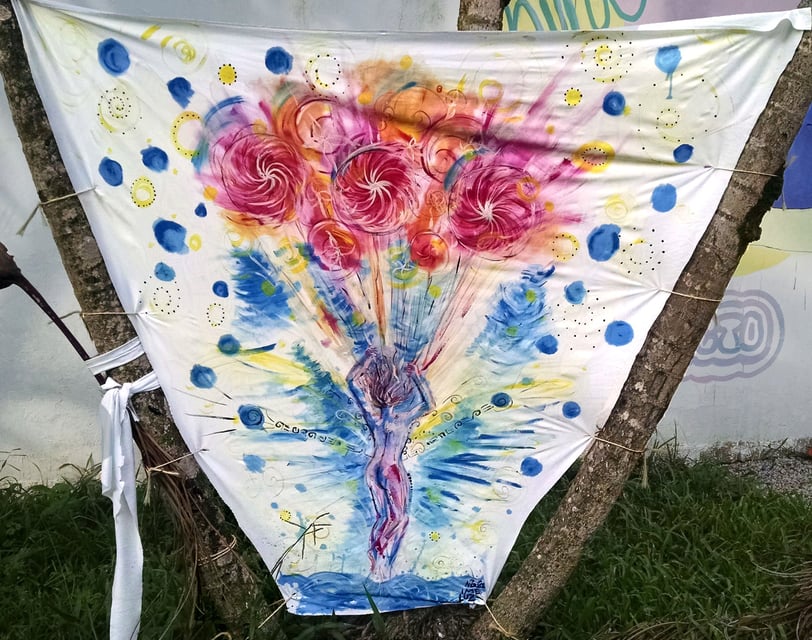 toile tendue entre deux arbes avec peinture représentant un corps s'envolant emmené par des genre de ballons 