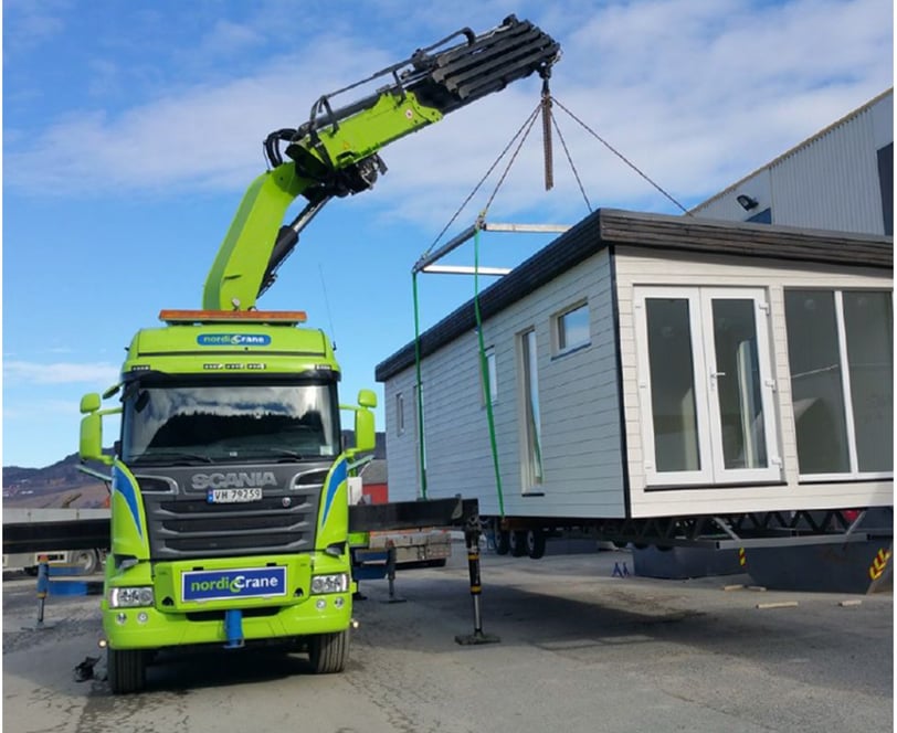 House being lifted onto a truck by a knuckle boom lorry mounted crane.
