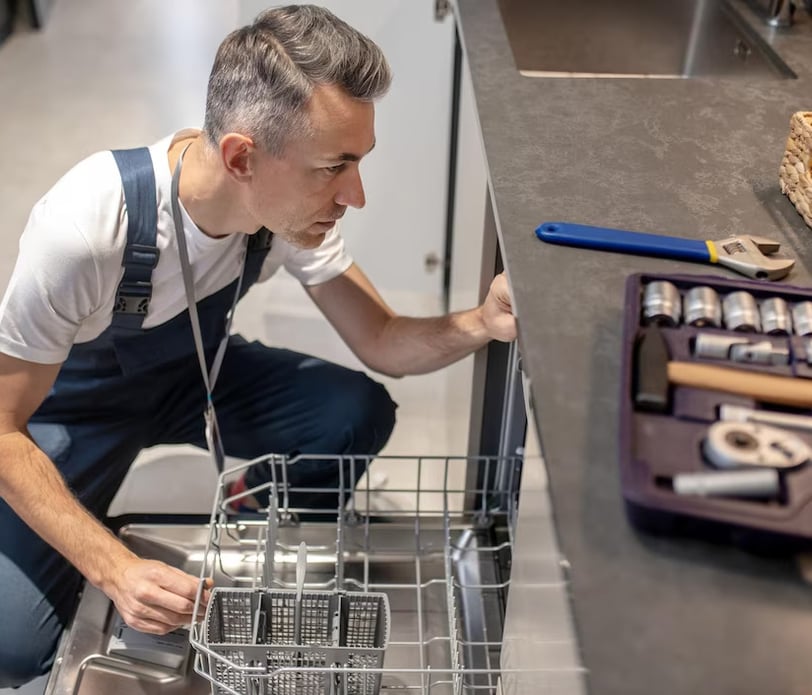 a man in overalls and overalls is looking at a dishwasher