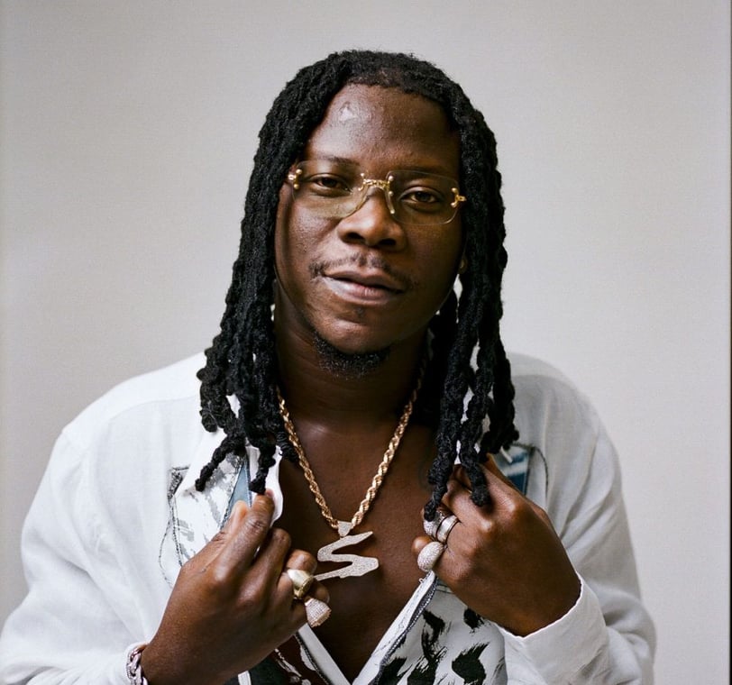 Stonebwoy in a white shirt with a golden chain.