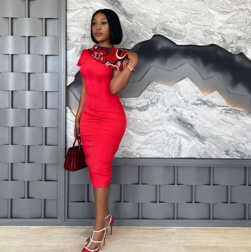 Efia Odo in a red overall dress holding a wine bag.